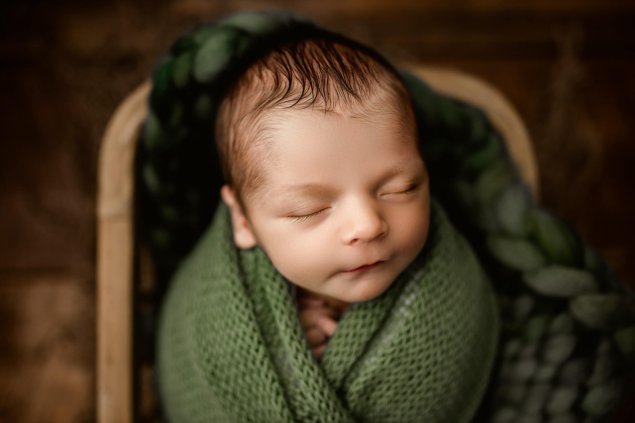 baby wrapped in green knit posed in newborn prop captured by woodstock newborn photographer, alexes Renea