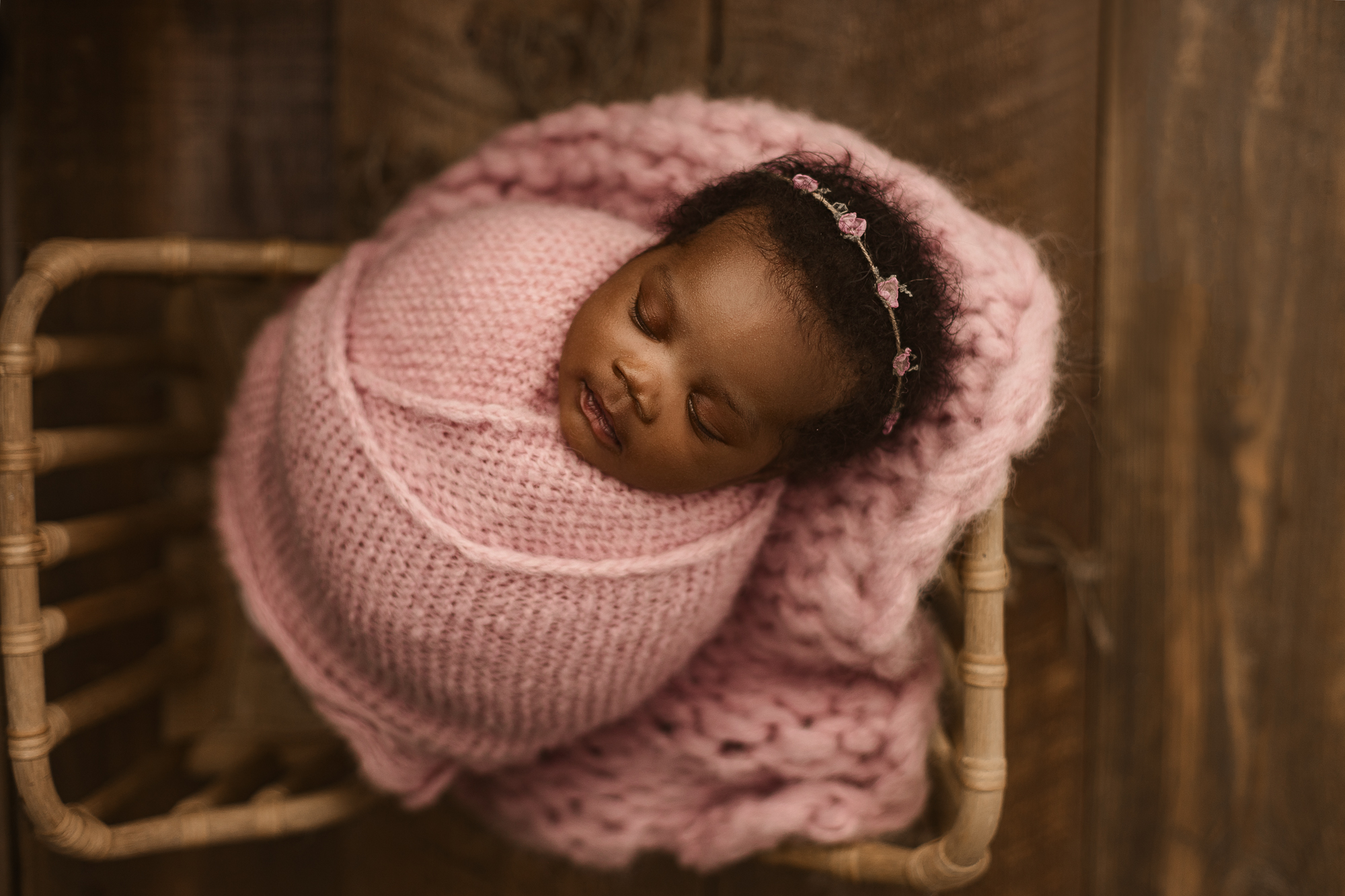 Atlanta doulas baby during newborn portrait session swaddled in pink posed in baby prop bed