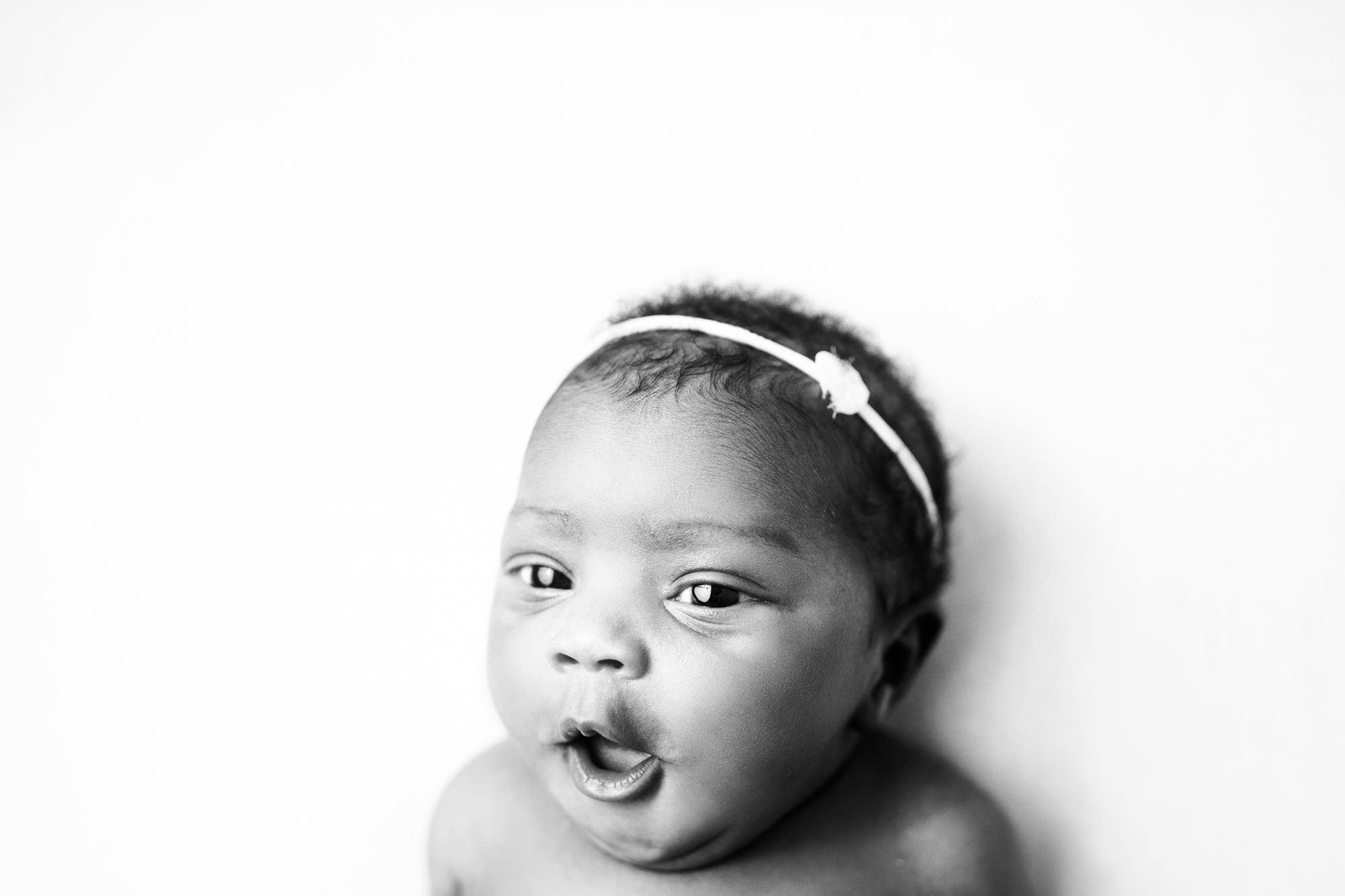 awake black and white image of baby looking at camera smiling