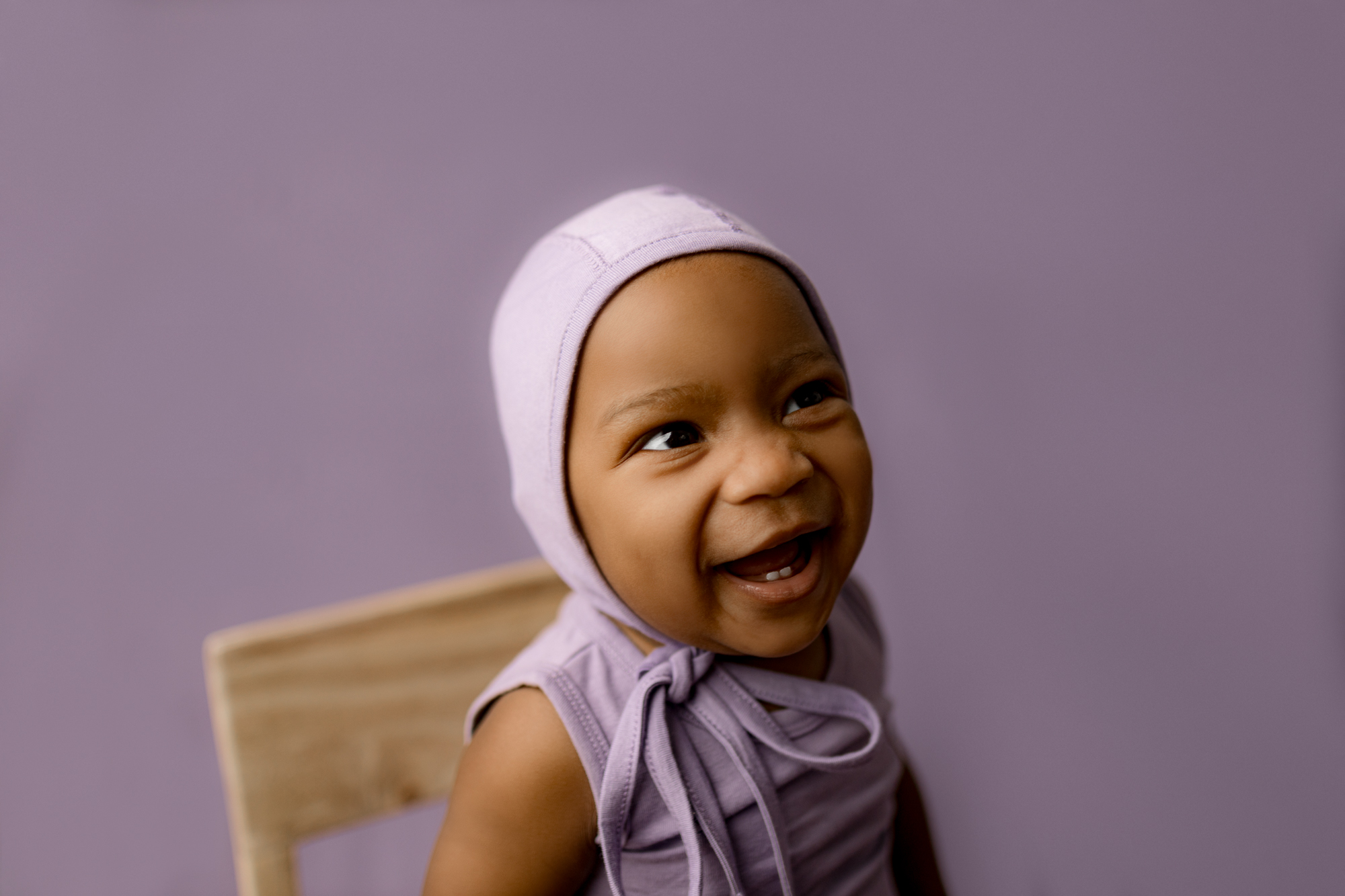 atlanta milestone session of baby smiling with purple bonnet